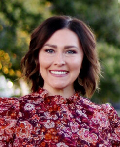 photo of woman's face in floral shirt in front of greenery